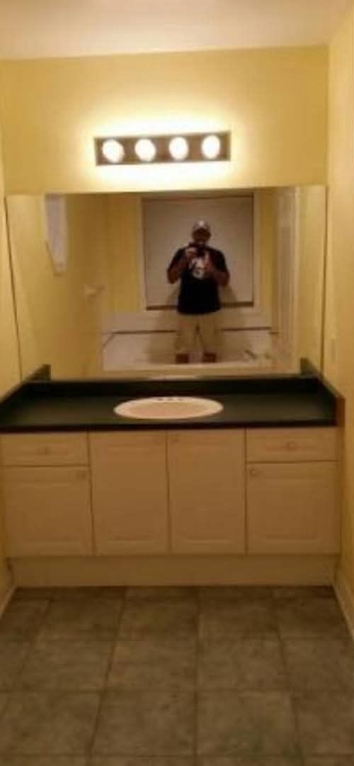 Dated bathroom with a single sink vanity and yellow walls