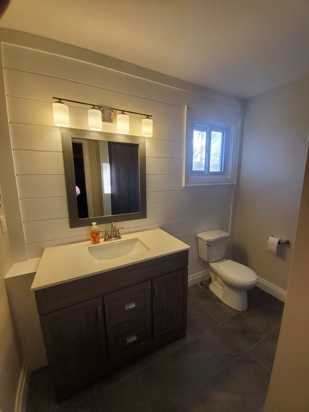 Bathroom with a shiplap feature wall, grey vanity and framed mirror