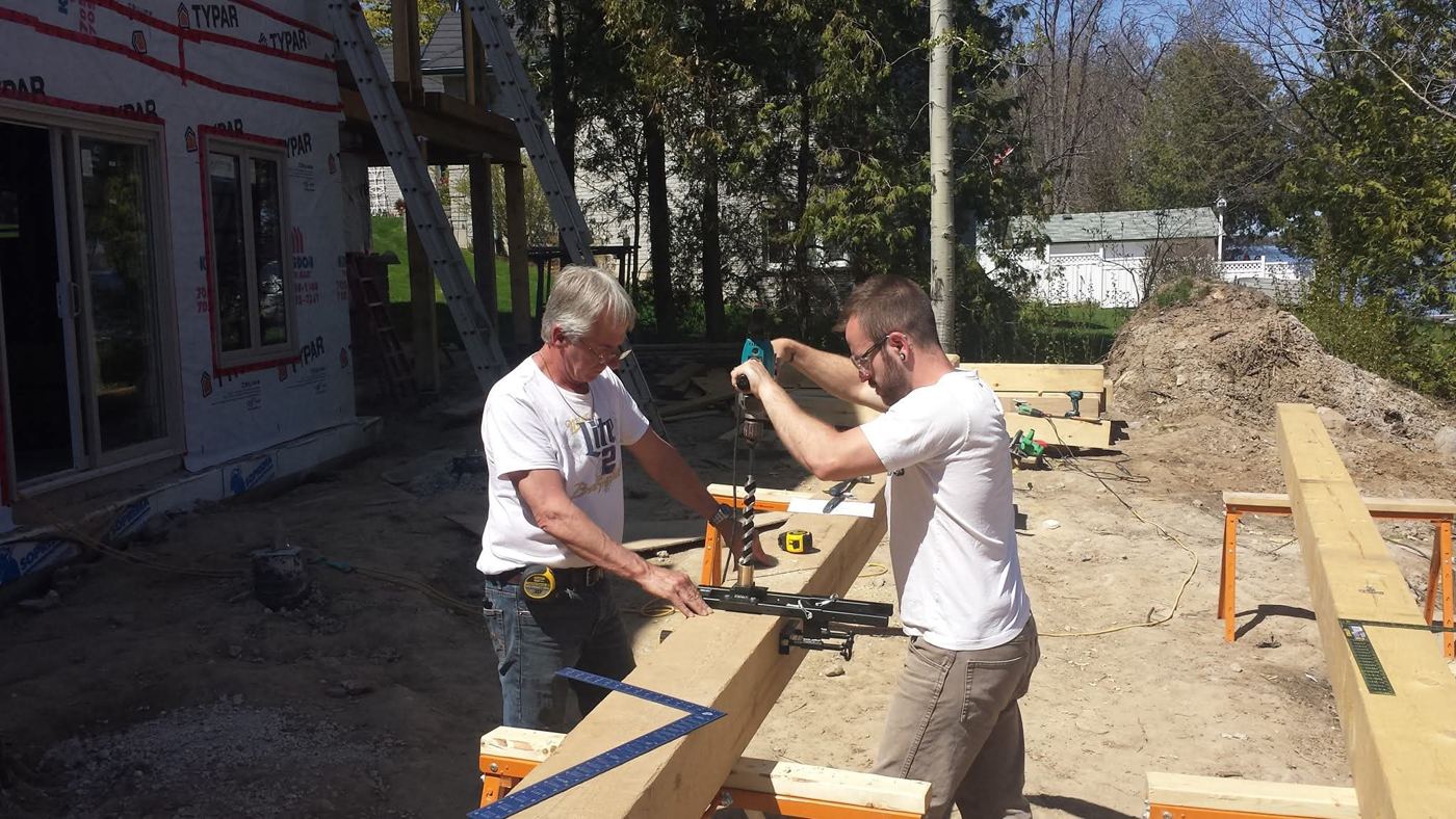 Davin’s father and brother boring a timber on a job site