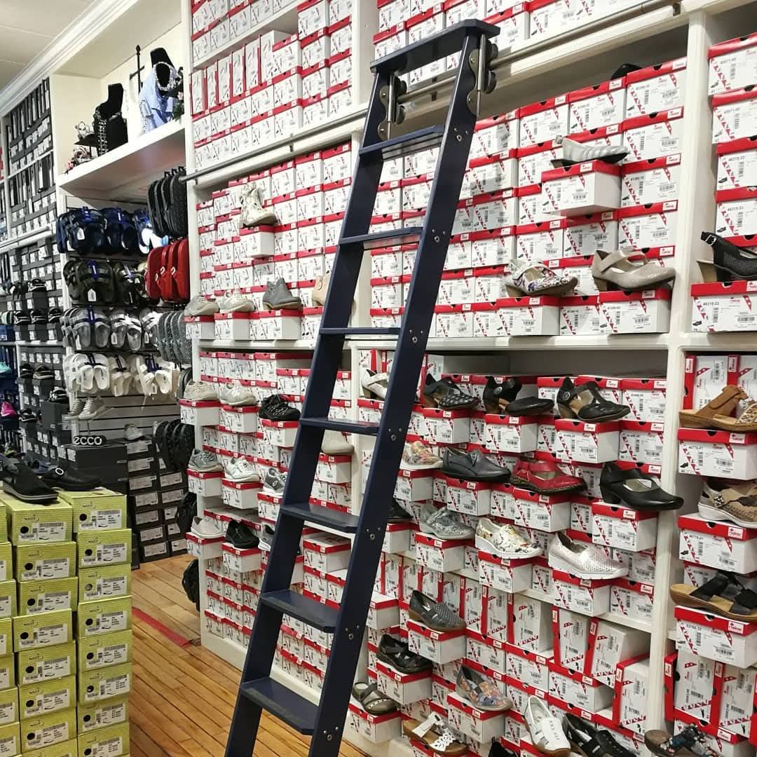Navy rolling ladder on a wall of shoe boxes