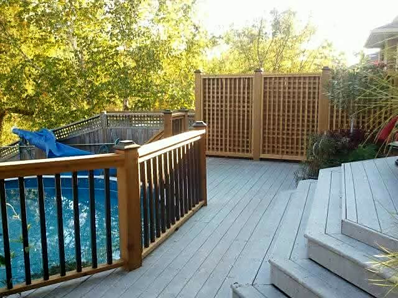 Deck with wood railing and lattice screens beside a pool