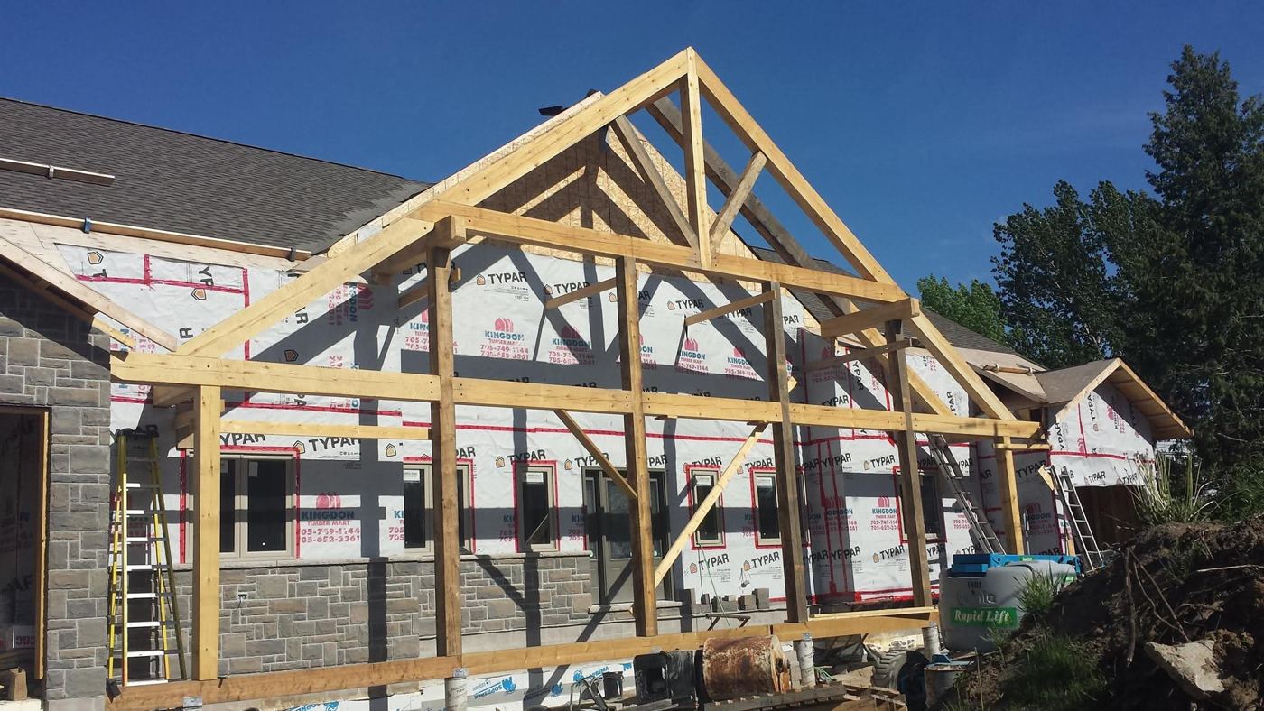 Raw timber frame porch standing against a house under construction