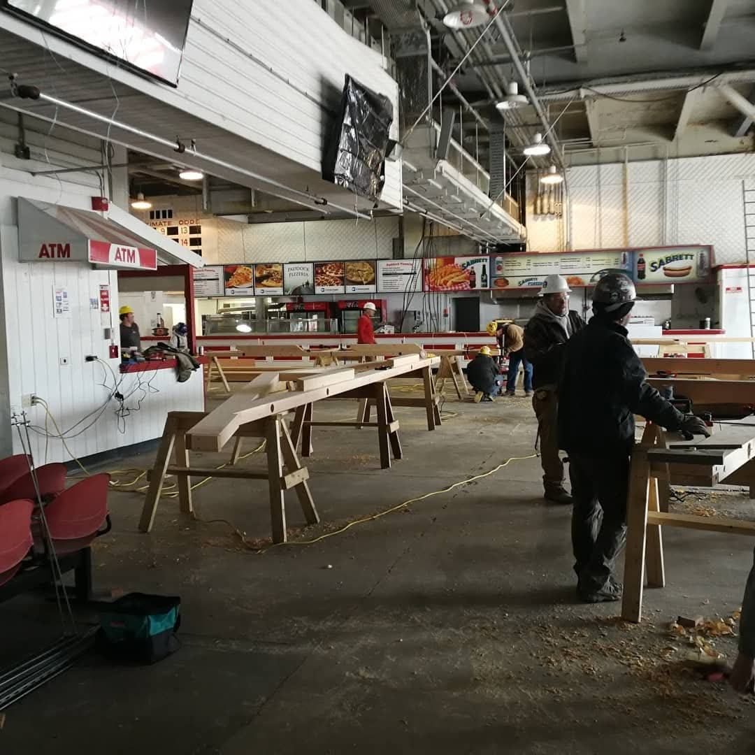 Crew working timbers on sawhorses inside the racetrack concourse