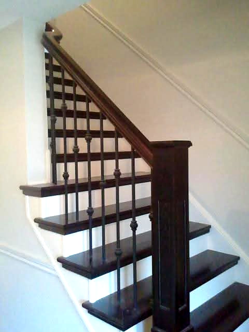 Dark newel post and handrail with iron spindles