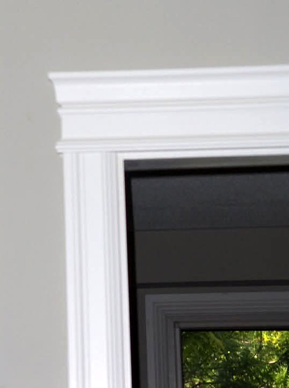 Close view of layered white header trim at a doorway corner